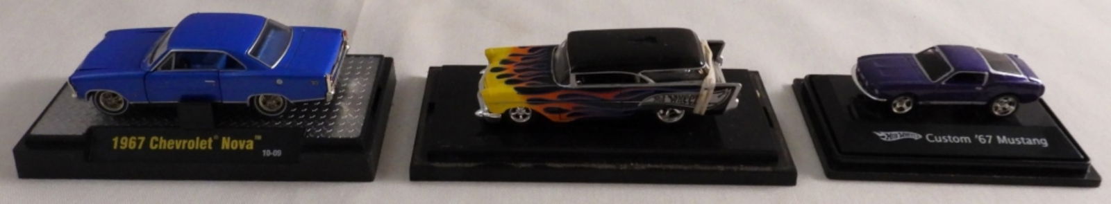 (3) Hot Wheels In Hard Display Cases: 1) 1967 Chevrolet Nova. 2) Custom "67 Mustang. 3) 1957 Chevy Nomad