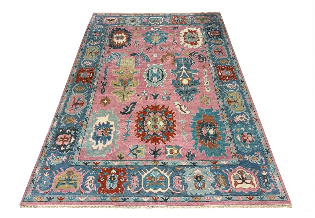 Oushak D185 size 9'9" x 13'10" hand-knotted: No Reserve Oushak D185 9'9"x 13'10" This rug presents a vibrant Oushak design, celebrated for its oversized floral motifs, open layout, and luminous color palette. The soft pink field serves as a chee