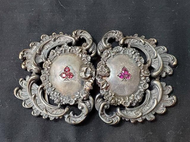 Ladies Antique Sterling Silver Belt Buckle: Ladies Antique Sterling Silver Belt Buckle measuring 3.5 inches by 2 inches and weighing 31.55 grams. At the center of each half is a 3 pinkish red stoned club motif. In good condition, small indentio