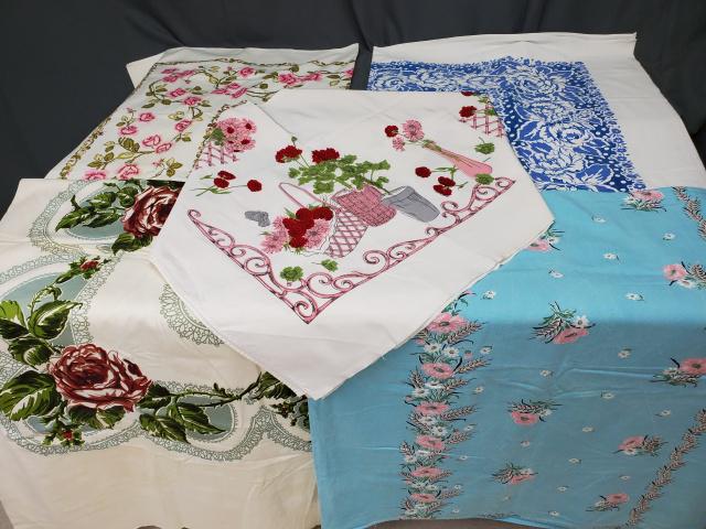 Group of 5 Vintage Printed Tablecloths: Group of 5 Vintage Printed Tablecloths includes a cotton rayon with pink and red flowers; a cotton rayon aqua with pink flowers; a cotton cloth with large green and red flowers some edge wear exists;