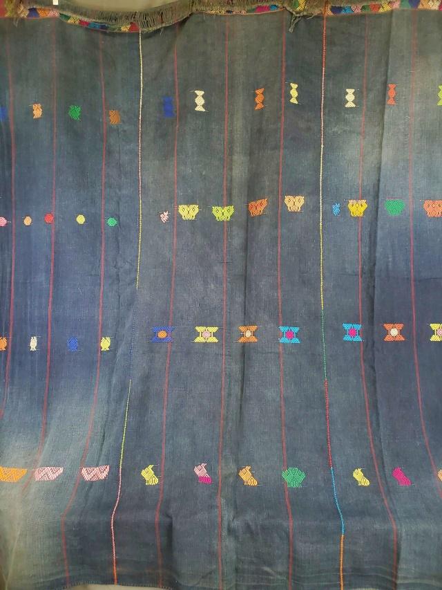 Vintage Indigo Denim with Hand Embroidery: Vintage indigo denim cotton panel, hand pieced in three vertical sections with colorful embroidery stitches, with small colorful woven motifs including birds, fox, and other geometric figures, measure