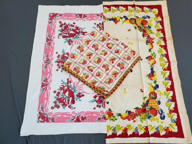 3 Vintage Printed Tablecloths - Group 2: 3 Vintage Printed Tablecloths, Group 2 consists of Colorful Fruit with red frame, rayon, 51x52, overall spots and discoloration. Red fruit with pink bows, cotton, 50x47, storage line discoloration, an