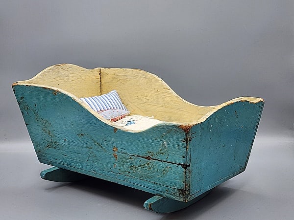 Vintage Wood Painted Blue Cradle with Bedding: Vintage Wood Painted Blue Cradle Measures 13.5 x 8 x 7". It is painted blue on the outside and a pale yellow on the inside. The bedding includes a mattress covered in blue and white ticking, a white l