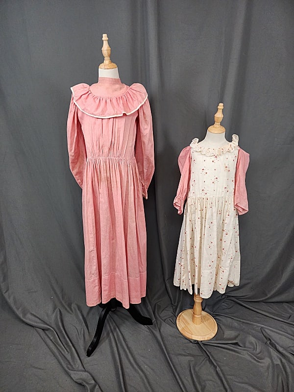 2 Vintage Girls Dresses with Ruffles: 2 Vintage Girls Dresses with Ruffles. Includes ivory with rose print dress and pink chambray sleeves. Buttons in the back but they are missing. Measures flat 11 Bust, 11 Waist, Roomy Hips, 14 Sleeves,
