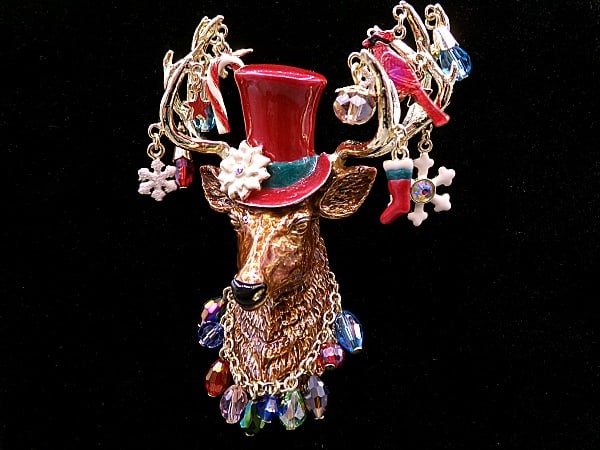 Large Kirks Folly Enamel Reindeer Brooch/Pendant: Large Kirks Folly Enamel Reindeer Brooch/Pendant measuring 3.5'' tall by 3'' wide. Featuring a noble reindeer in a maroon top hat, necklace, and its antlers decorated in various winter charms and dang