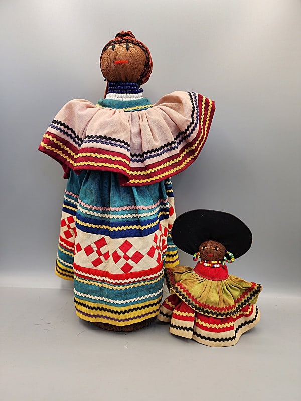 2 Ethnic Seminole Indian Dolls: 2 Ethnic Seminole Indian Dolls. Group includes a 6" doll in tiered dress with rick rack trim, black hat, hand embroidered face with beaded earrings and necklace. Body is contracted of palmetto fiber h