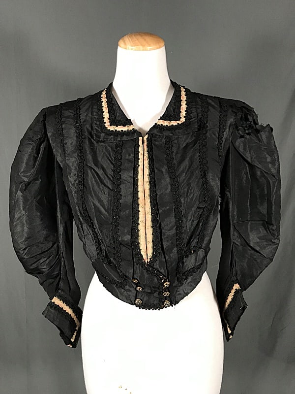 Antique Victorian Ladies Bodice: Antique Victorian Ladies Bodice. This lovely black silk bodice features puff sleeves, double pleats at the shoulders, black passementrie trim throughout, and a double breasted front button closure. As