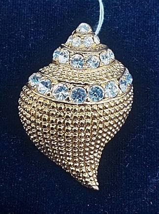 Conch Shell Brooch/Pendant by Kenneth Jay Lane: Conch Shell Brooch/Pendant by Kenneth Jay Lane. The goldtone conch shell brooch by Kenneth Jay Lane features a textured surface highlighted by clear rhinestone accents. As well as a hinged bail for an