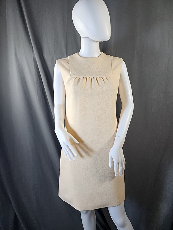 Vintage Donald Brooks Dress: Vintage 1960s ivory mini dress feels like a polyester crepe or poly wool blend. Has pleating under square yoke at bust. Metal zipper at back. 2 side pockets. Lined in ivory polyester. Flat measurement
