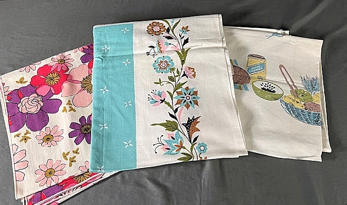 3 Vintage Cotton Printed Tablecloths - Florals: 3 Vintage Cotton Printed Tablecloths - Florals. Includes a white with purple and pink flowers, measuring approximately 50" x 50"; a white with turquoise inner border surrounded by pink, turquoise and