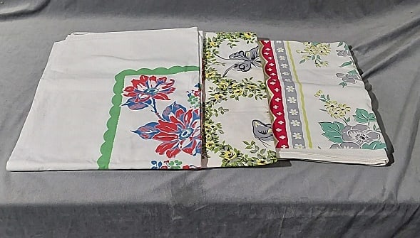 3 Vintage Printed Tablecloths-Grey Floral: 3 vintage printed tablecloths-Grey Florals. A white cotton with printed grey scalloped frame around yellow daisies and grey butterflies, measures 49 1/2" x 49", good condition with some areas of stain