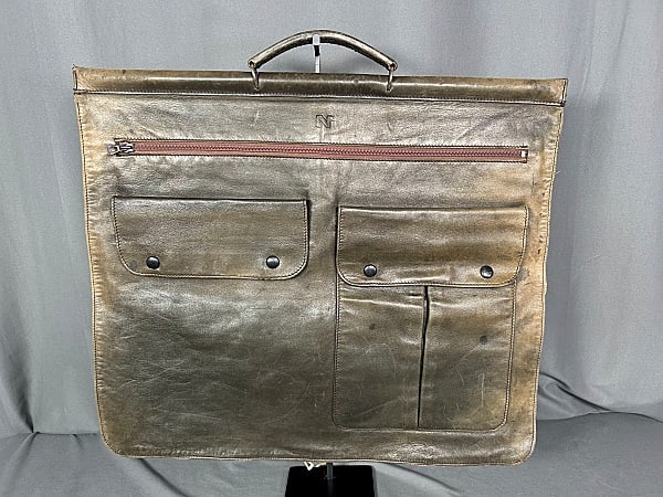 c1980 Nina Ricci Leather Garment Bag: c1980 Nina Ricci Leather Garment Bag. The lot includes 1 vintage c1980 olive green leather folding garment bag by Nina Ricci. Made in France this bag features a tan interior with a large zip compartme