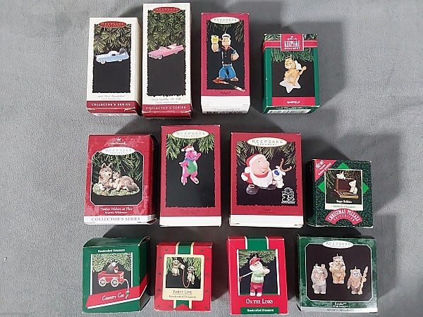 12 80s and 90s Mixed Boxed Hallmark Ornaments: 80's and 90's Mixed Boxed Hallmark Ornaments. The lot includes 12 1980s and 90s mixed boxed Hallmark ornaments. Featuring 1 c1996 "1959" Pink Cadillac De Ville, 1 c1989 golfing Santa, 1 c1987 Happy Ho