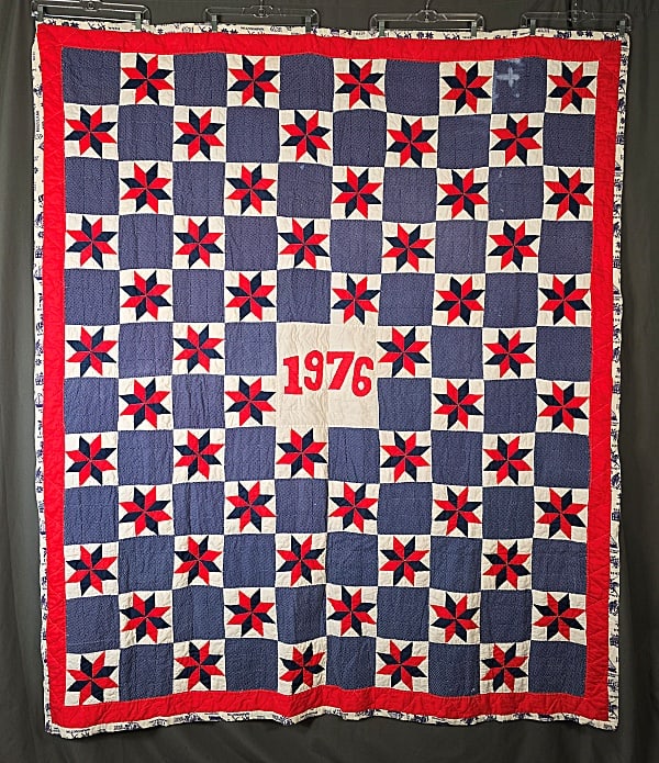 Vintage 1976 8 Pointed Star Quilt: Vintage Bicentennial 1976 8 Pointed Star Quilt measuring 65x77". Center white square with red 1976 machine appliqued, surrounded by red and blue 8 pointed star blocks with alternating blue print block