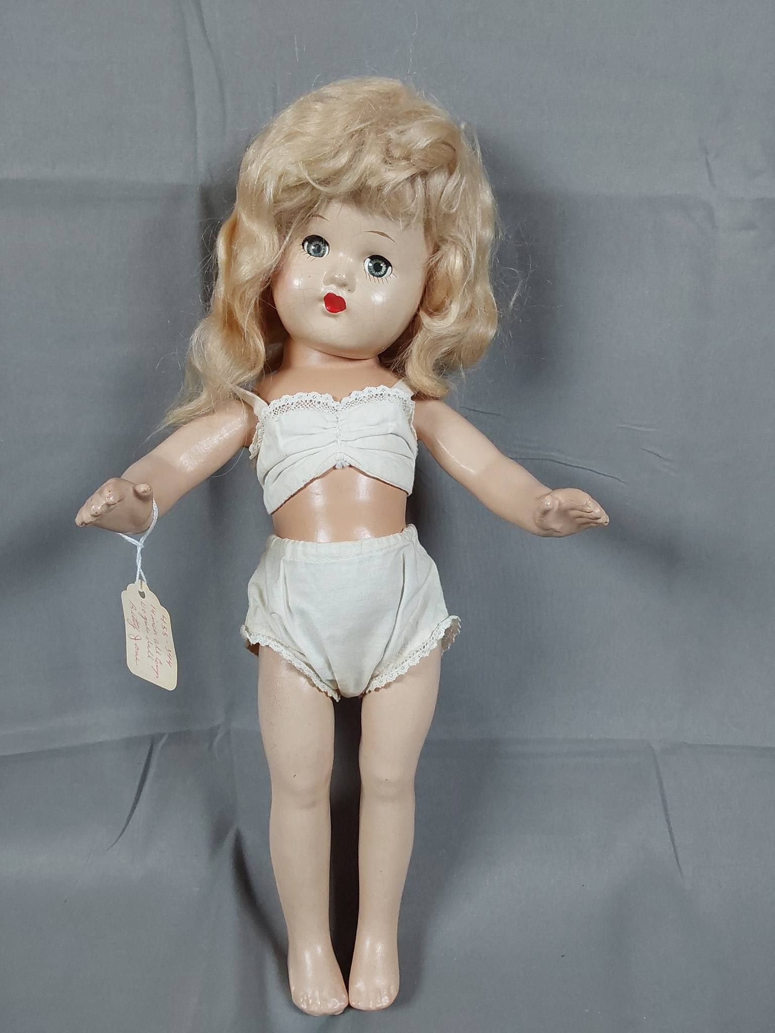 Blonde 16 Inch Composite Doll - Betty Jane: Blonde 16 inch Composite Doll. Doll has hand painted face with blue sleep eyes, white undergarments. Jointed neck, arms and legs. Possibly a Betty Jane Vogue doll according to old tag. In good conditi