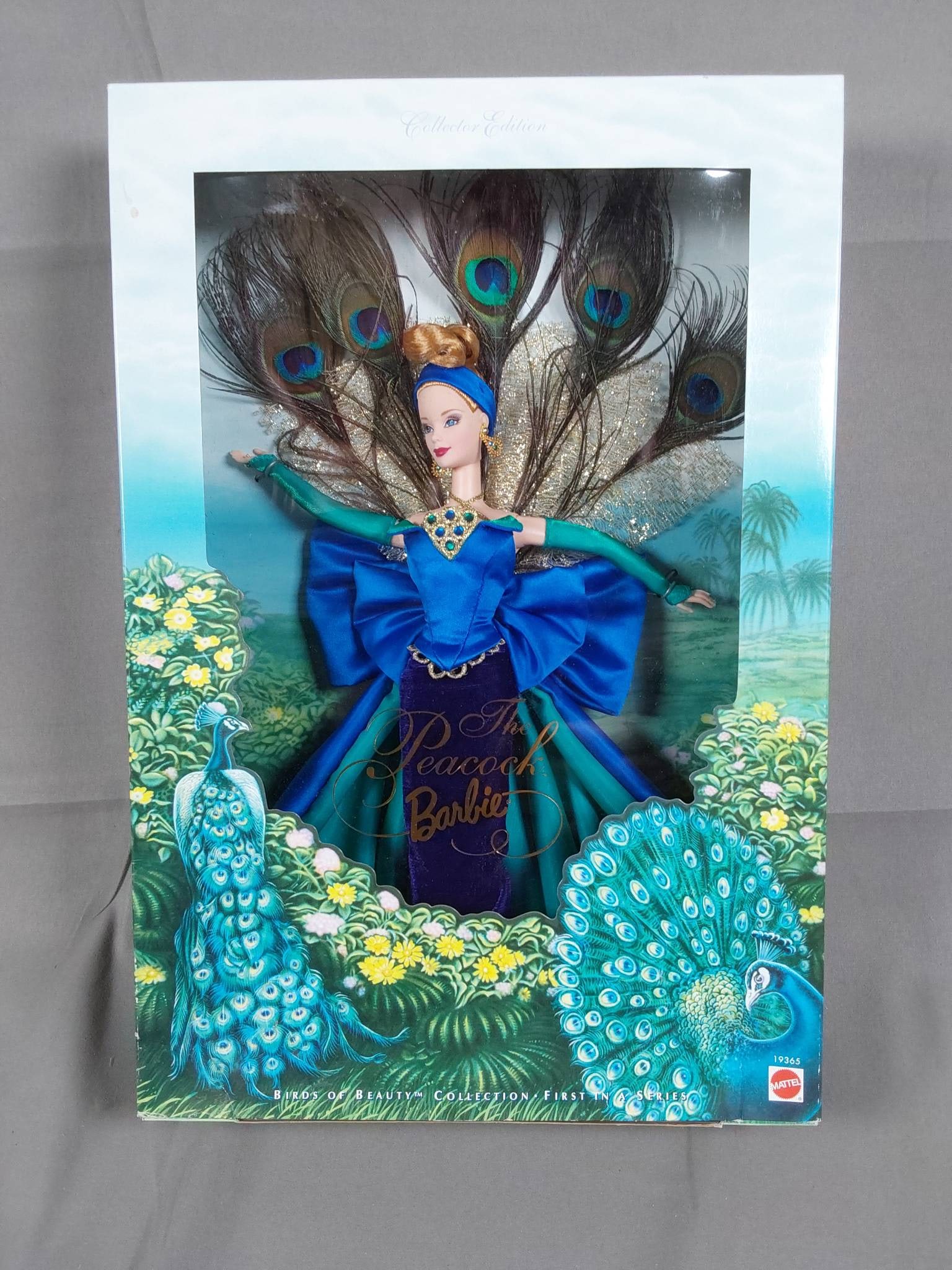 The Peacock Barbie Doll 1998 Model 19365 ?: The Peacock Barbie Doll, Model 19365, is part of the Birds of Beauty Collection by Mattel, First in the Series released in 1998. The doll is dressed in vibrant shades of blue and green with golden acc