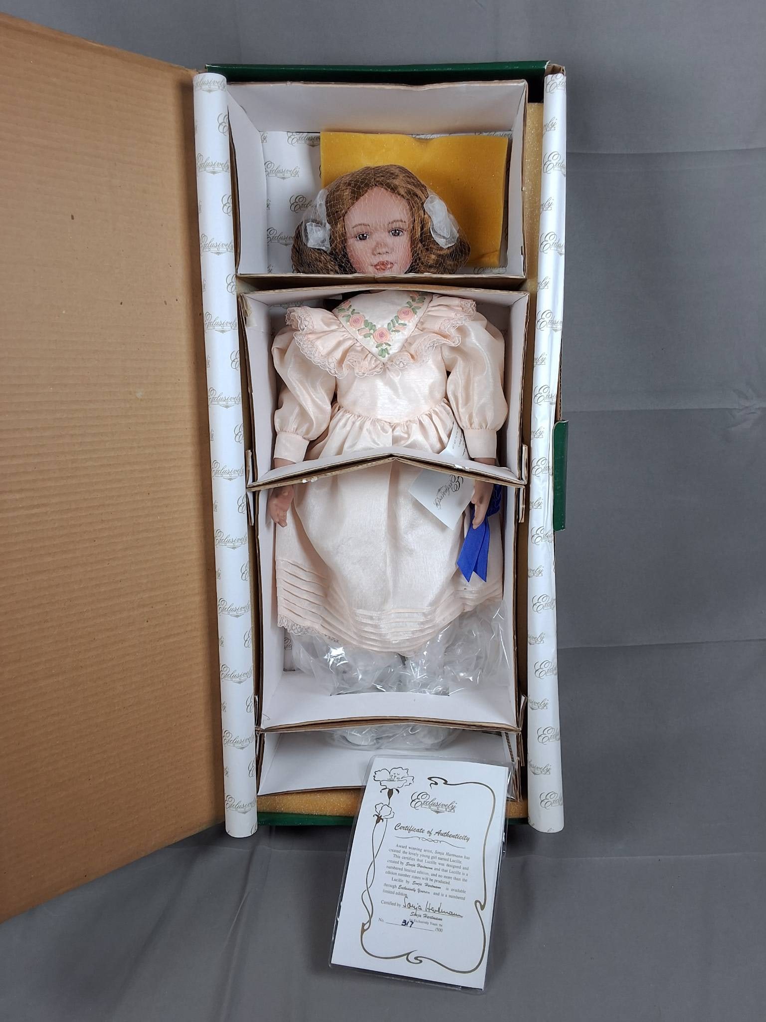 Lucille by Sonja Hartmann: Lucille by Sonja Hartmann measures 22 inches in height and is number 317 of a limited edition of 500 units. She is dressed in a light peach-colored dress featuring a floral embroidered collar and deli