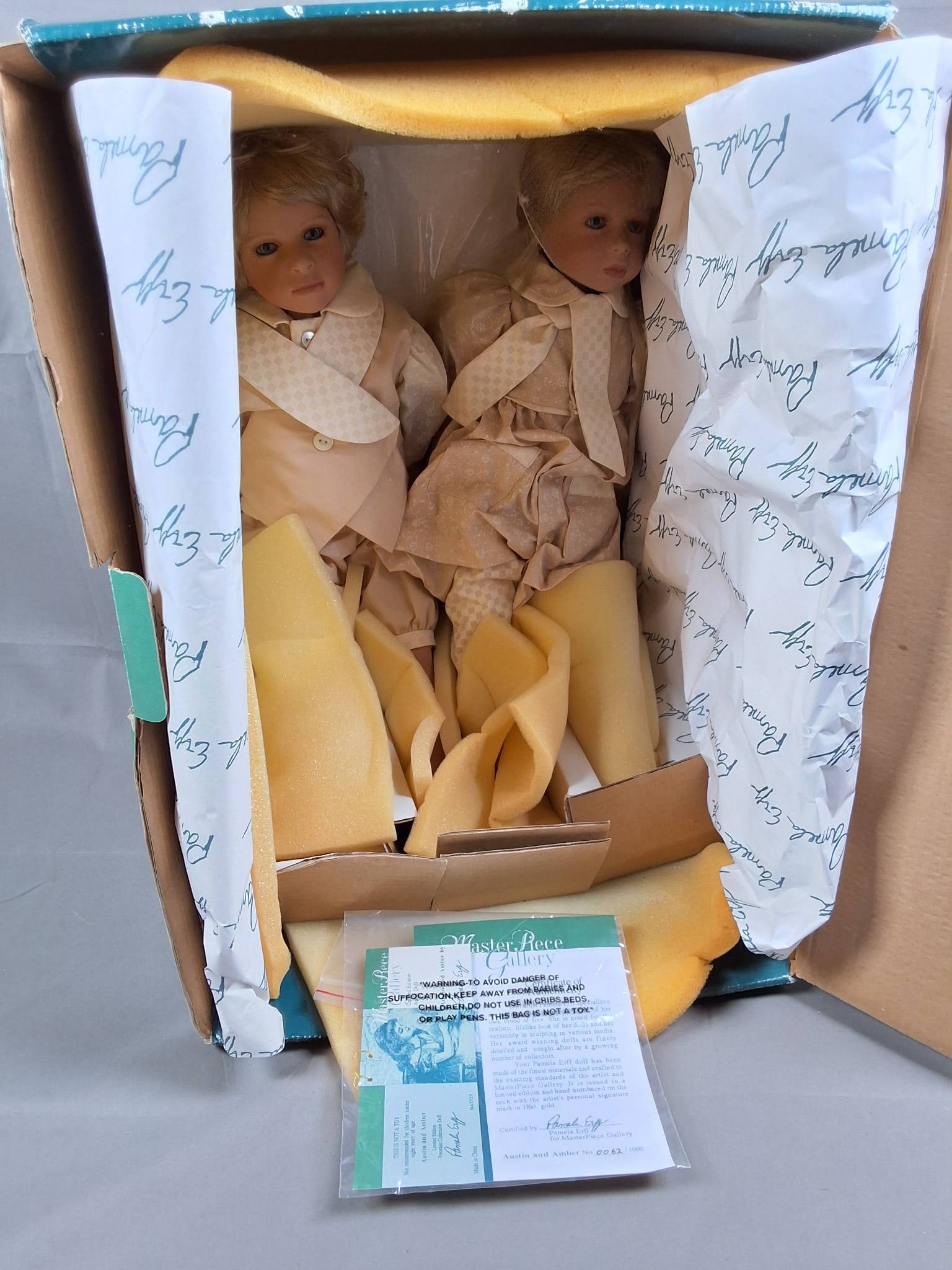 Austin and Amber by Pamela Erff: Austin and Amber, created by Pamela Erff, stand 19 inches tall and are numbered as 62 out of a limited edition of 1000. The dolls are clothed in complementary beige outfits; Austin wears a tailored su
