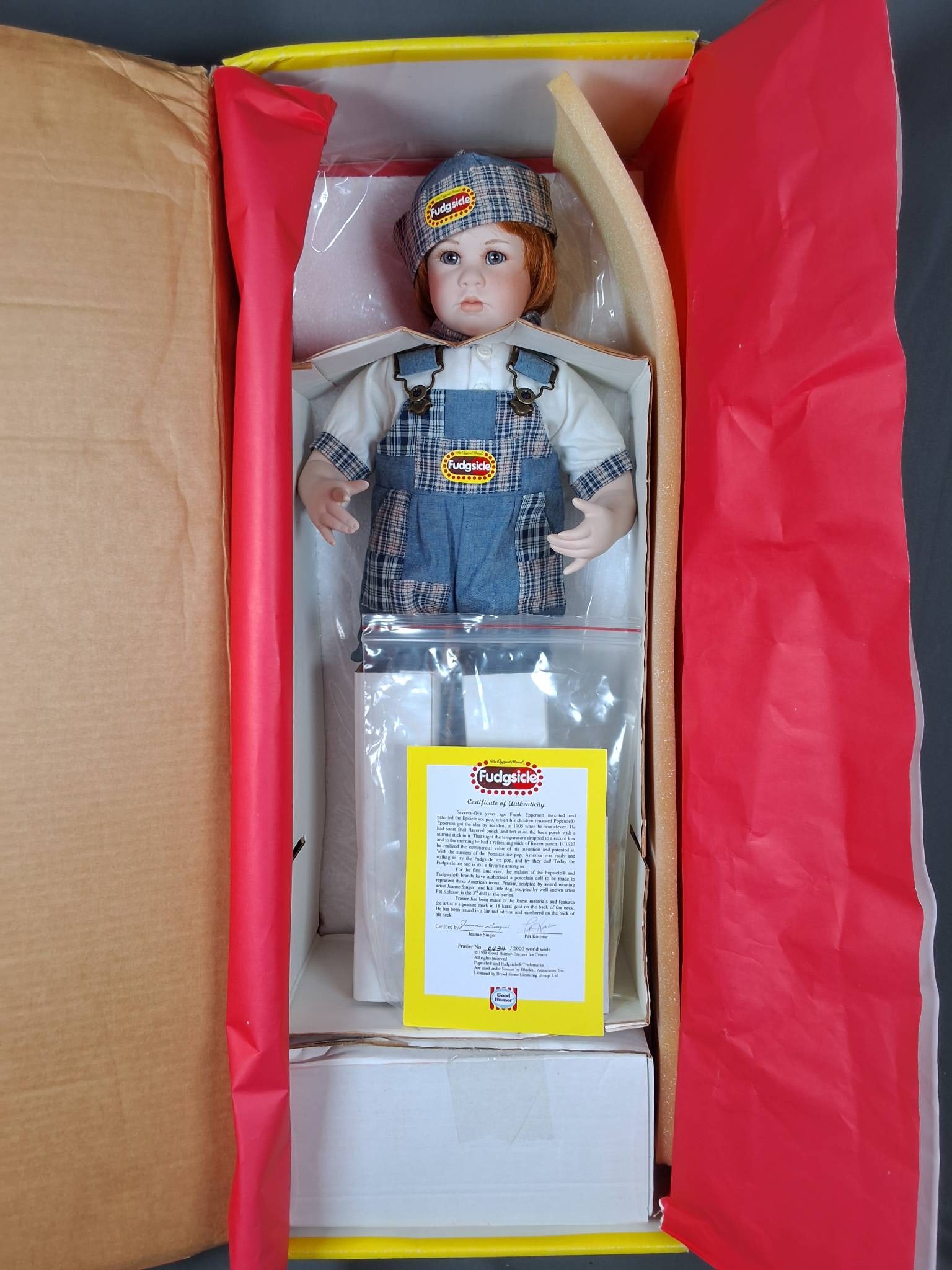 Frasier Fudgsicle by Jeanne Singer: Frasier Fudgsicle, porcelain doll designed by Jeanne Singer, stands 23 inches tall and is #434 of 2000. He is certified by Pat Kolesar and made by Good Humor-Breyers Ice Cream. Frasier wears patchwork