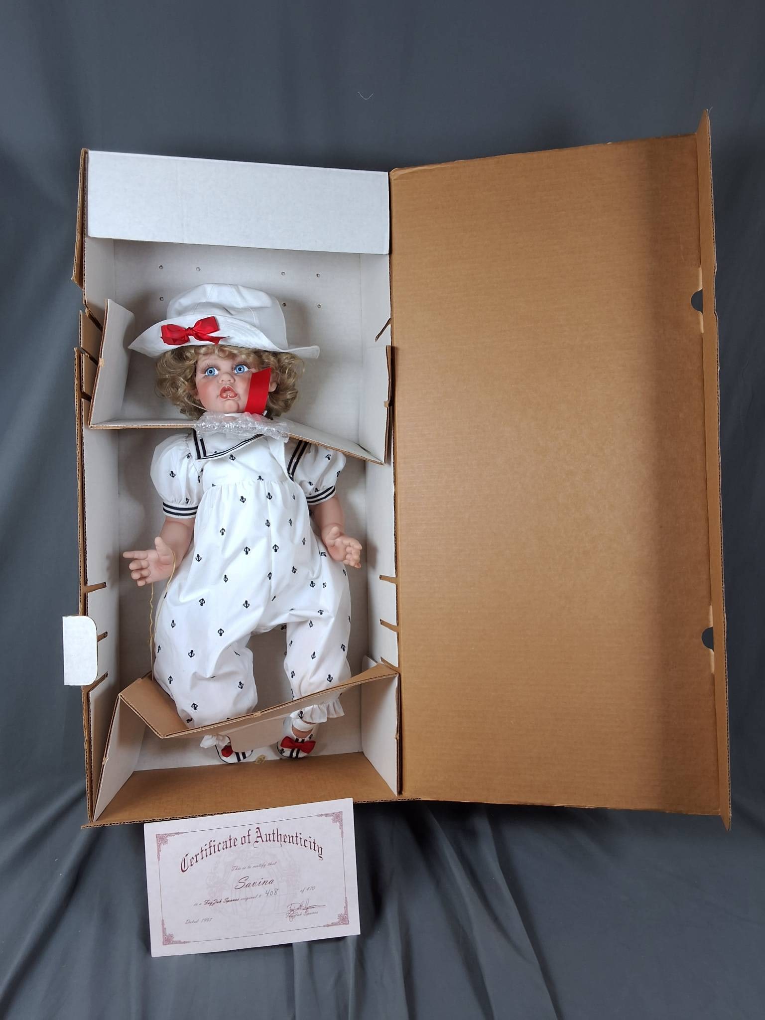 Savina by Fayzah Spanos: Standing at 22 inches tall, this 1997 vinyl doll is part of Fayzah Spanos' Precious Heirloom Dolls collection and comes with a Certificate of Authenticity as unit number 408 of 470. Savina wears a whi