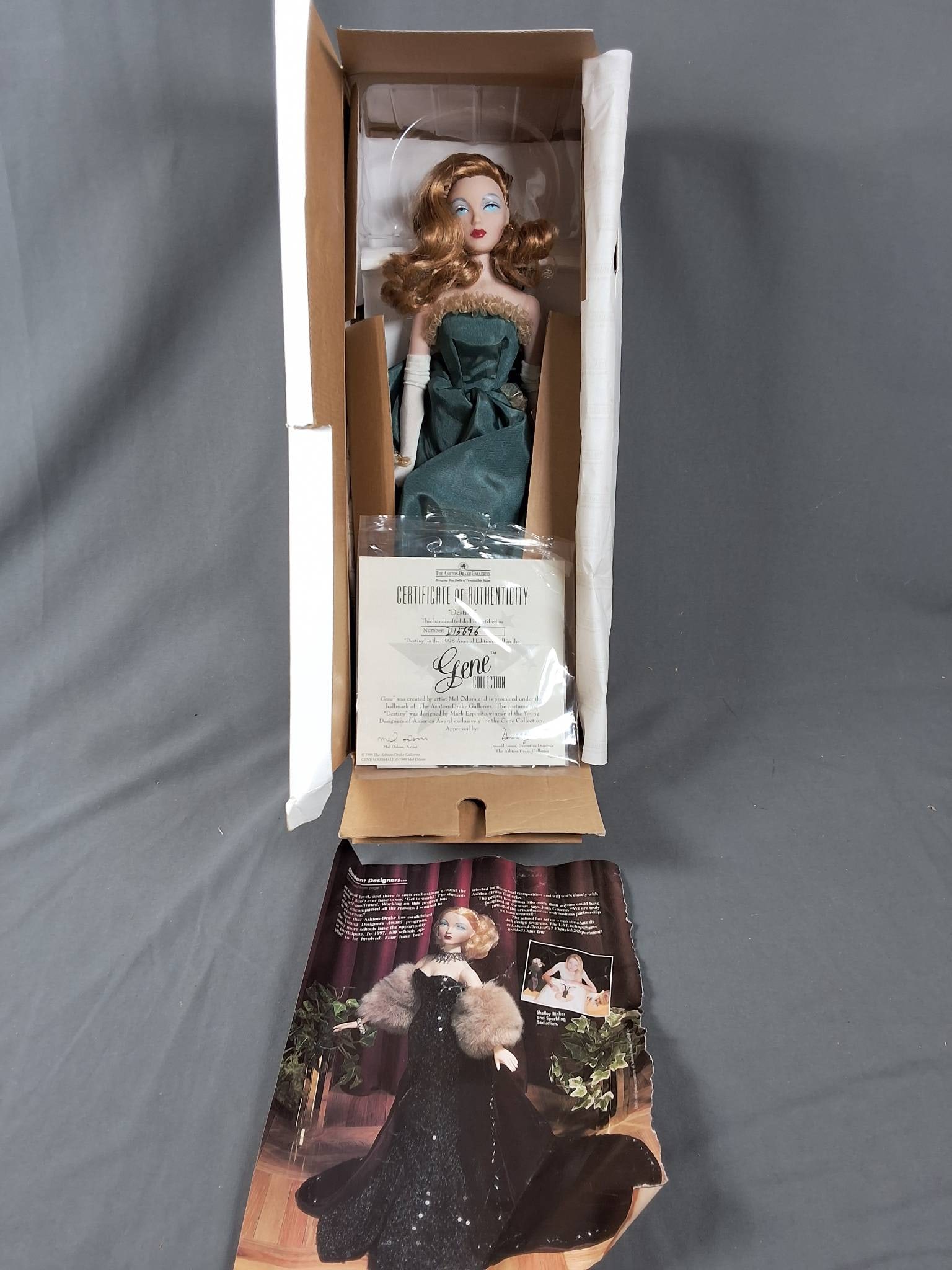 Destiny by Gene: Destiny by Gene is a 15-inch doll. She is dressed in a strapless teal gown with a textured design, featuring a structured bow-like accent at the waist. She also wears long white gloves and has styled 