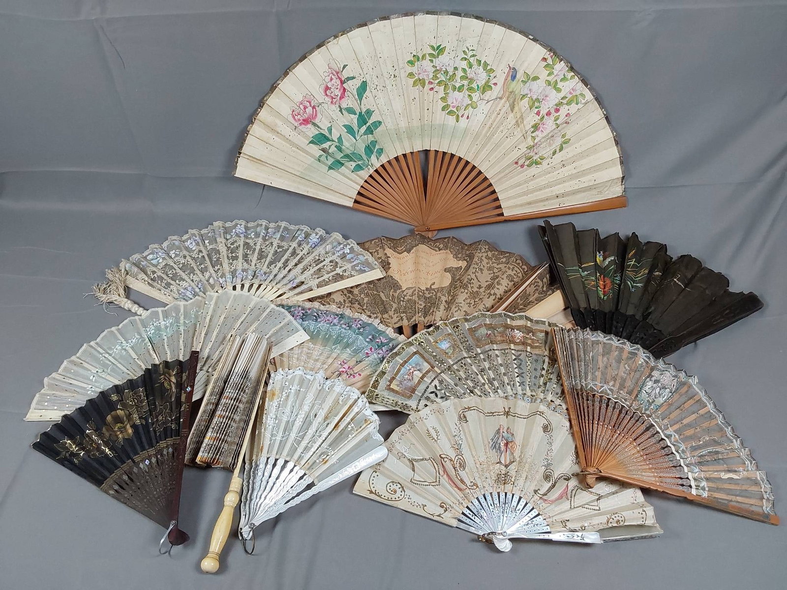 Lot of 12 Damaged Antique and Vintage Fans: Lot of 12 antique and vintage fans featuring both paper and fabric leaf, as well as wood guards and ribs. Includes carved bone components as well. Fans vary in size, ranging from 7 1/2" x 13" to 13" x