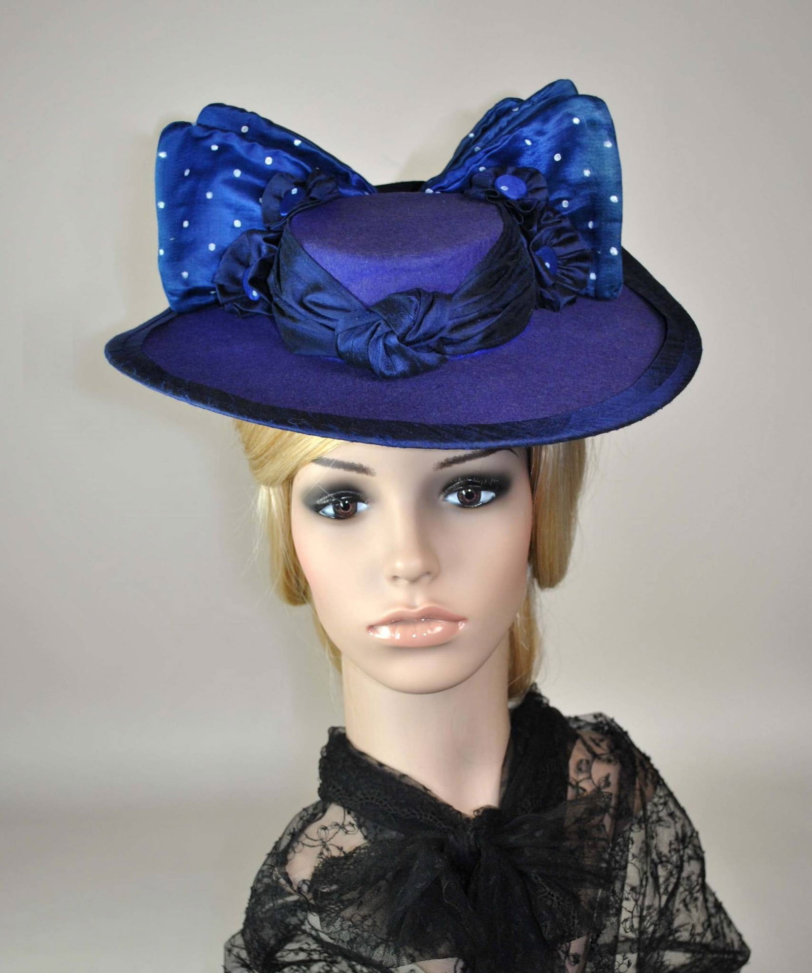 Antique Boater Style Hat: The hat is crafted in purple/blue wool felt and styled as a boater. Navy silk trims the edges, while blue satin wired bows decorate the back with meticulously hand-painted white dots. Additionally, ho