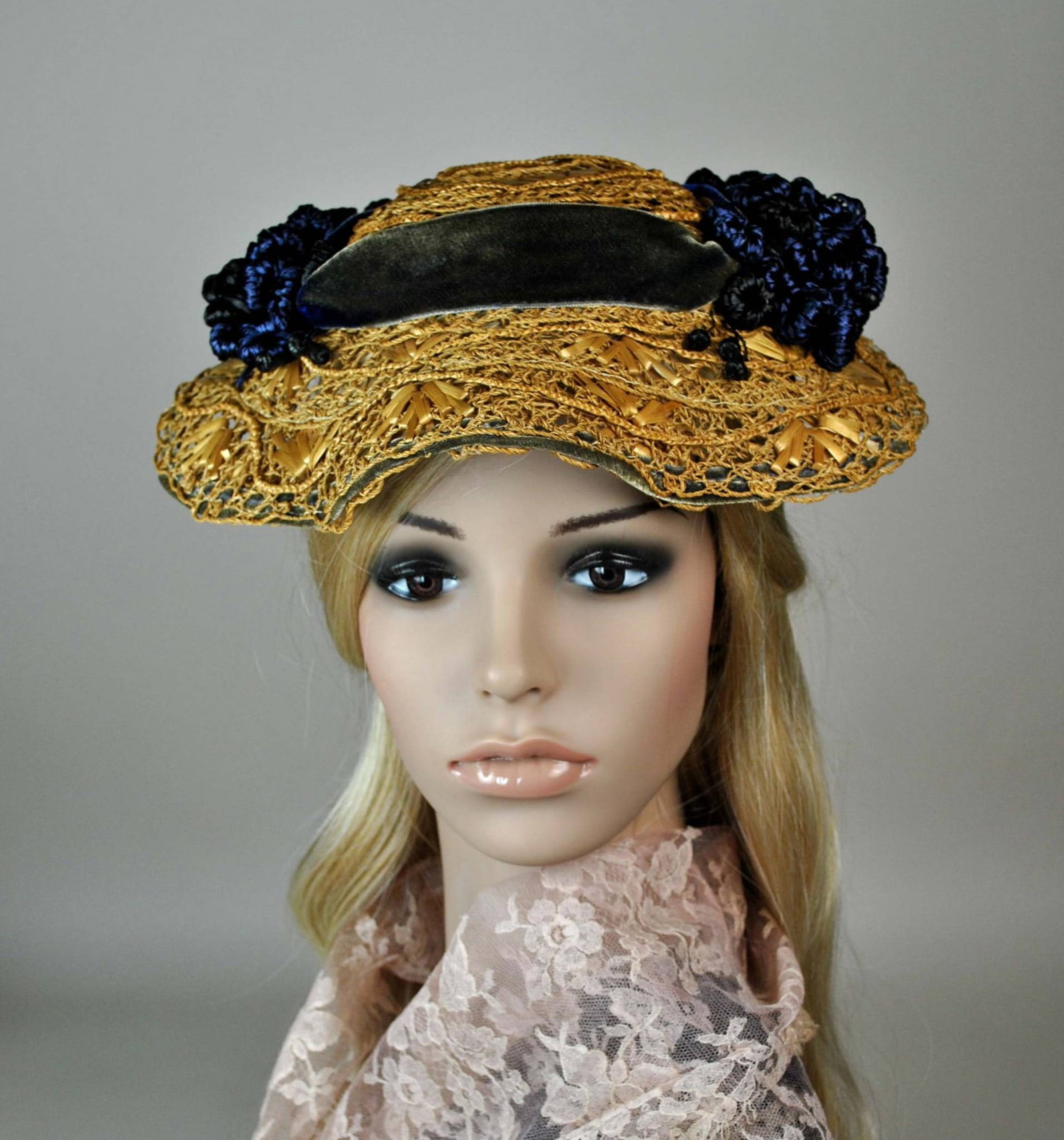 Vintage Straw Perching Hat: A vintage perching hat, with all the characteristics of an 1890s hat, has a natural fancy straw design featuring a small crown and fluted brim. The hat is adorned with a blue/gray velvet ribbon, compl