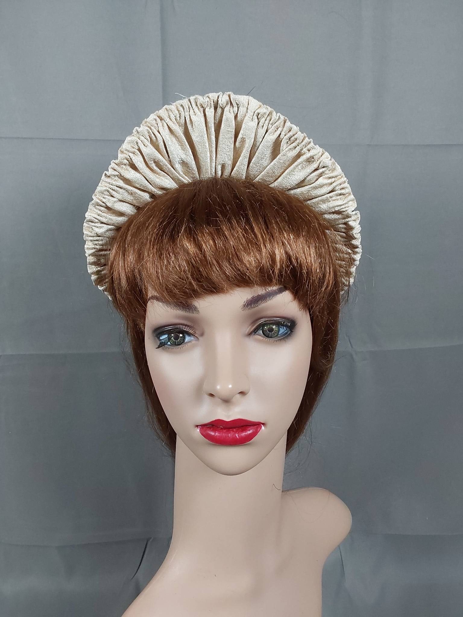 Antique 1880s Black Straw Bonnet: a small antique 1880s black straw bonnet, featuring a peaked brim. The bonnet has a woven decorative straw trim along the edge, lined with shirred golden beige silk on the front. An ostrich plume in c