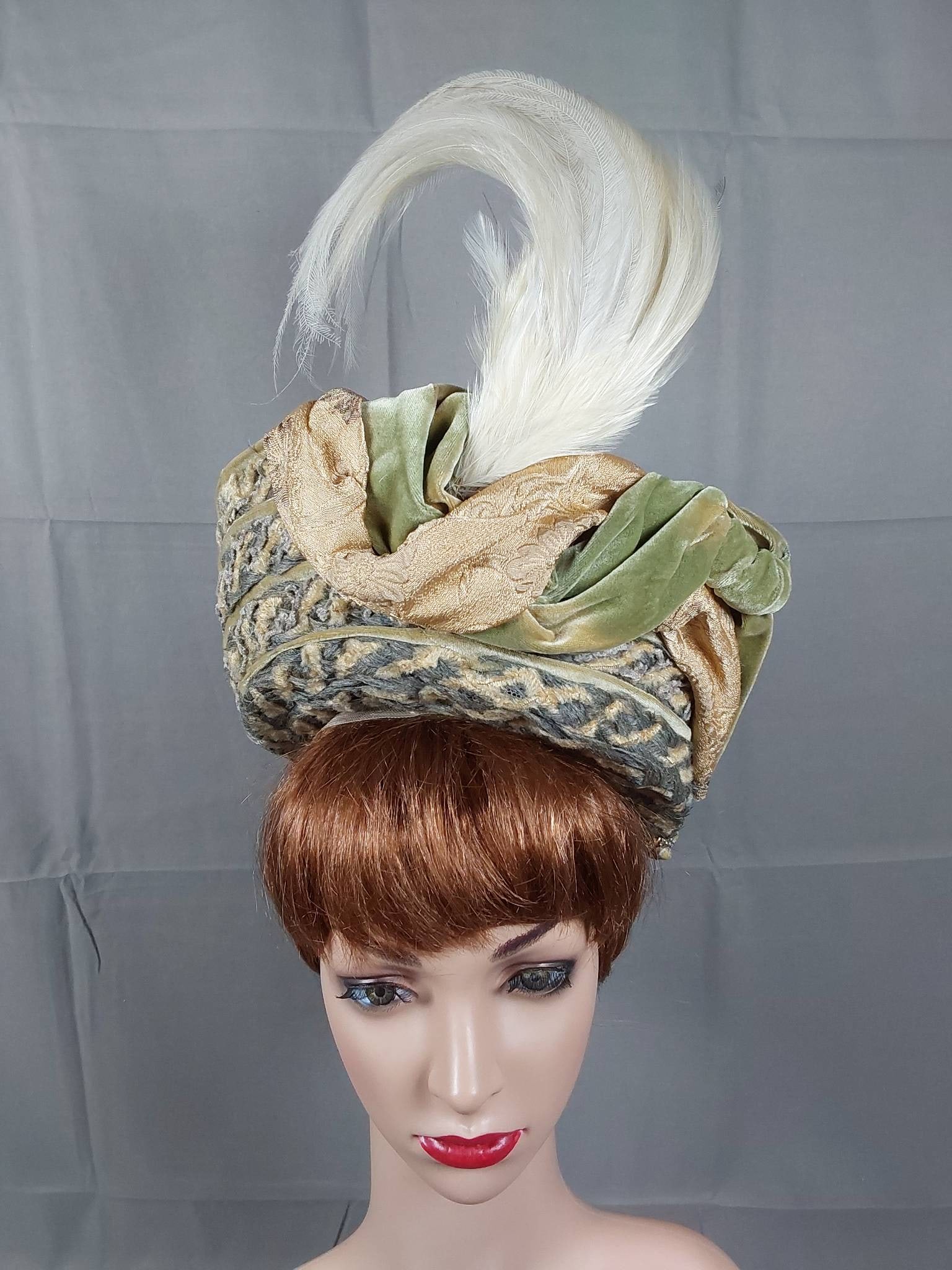 Early 20th Century Hat: An early 20th-century hat, circa 1905, featuring a wire frame covered in blonde and grey interwoven chenille and grey wool braid. The design includes narrow undulating bands of sage green velvet and g