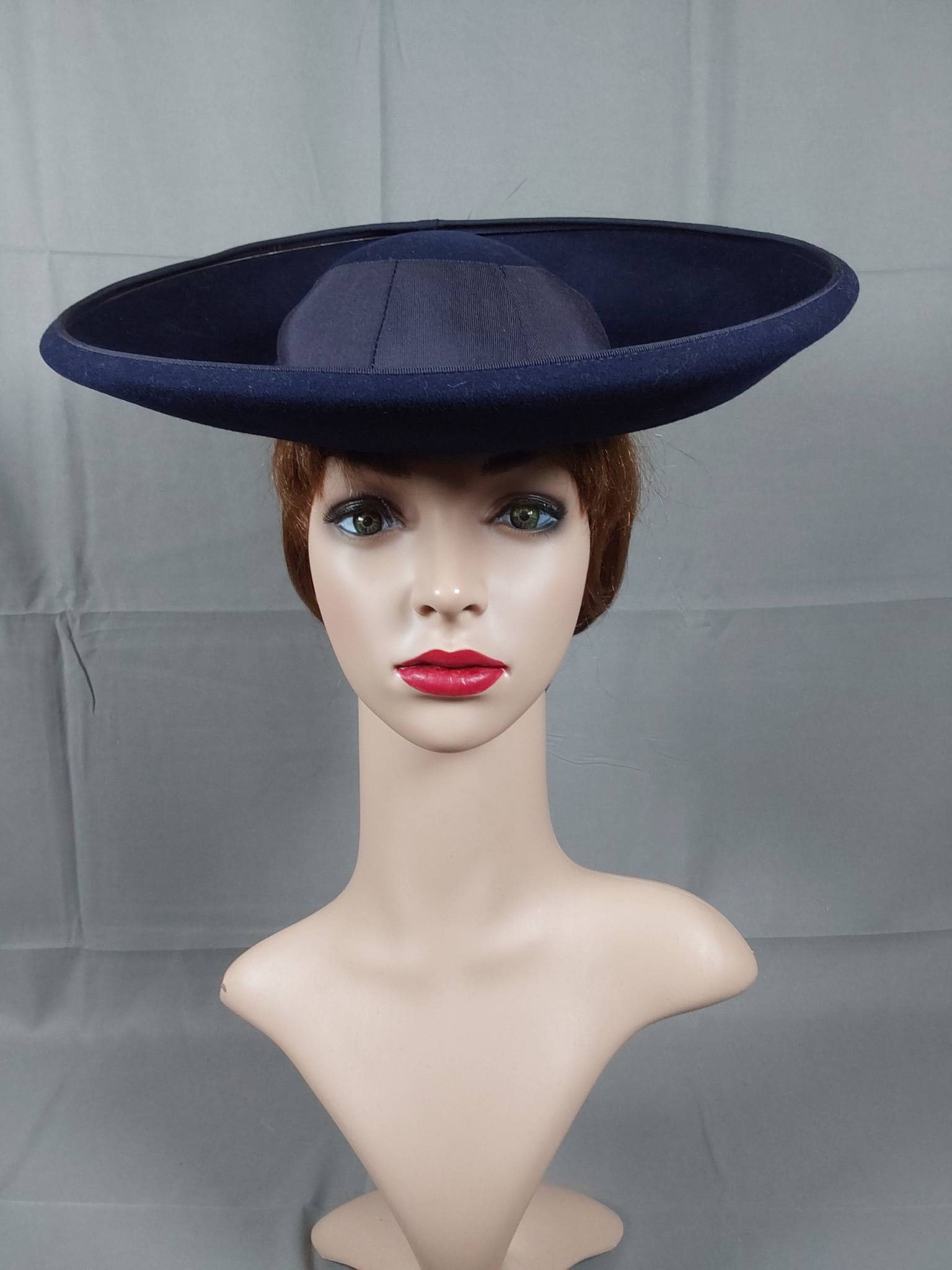 Vintage 1930s Navy Blue Madeline-Style Hat: A vintage 1930s navy blue wool felt Madeline style hat featuring a wide upturned brim, complemented by a navy blue pleated grosgrain ribbon band. The design includes a small round crown and an elastic