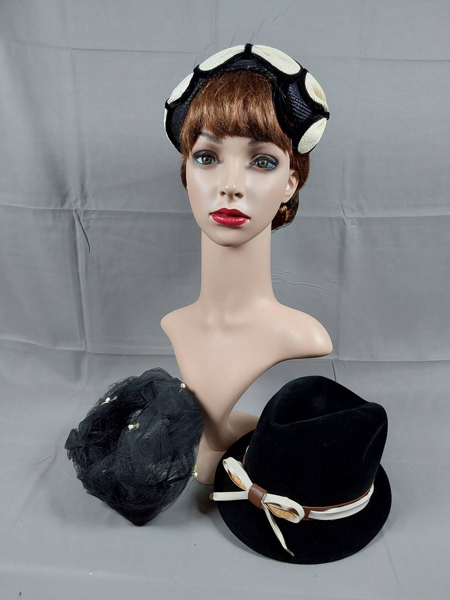 Group of 3 Vintage Hats 1950s-1960s: Group of 3 vintage ladies hats from the 1950s and 1960s. Includes a synthetic black straw cloche-style hat with ivory synthetic straw bows trimmed in black velvet ribbon. Also features a braided black