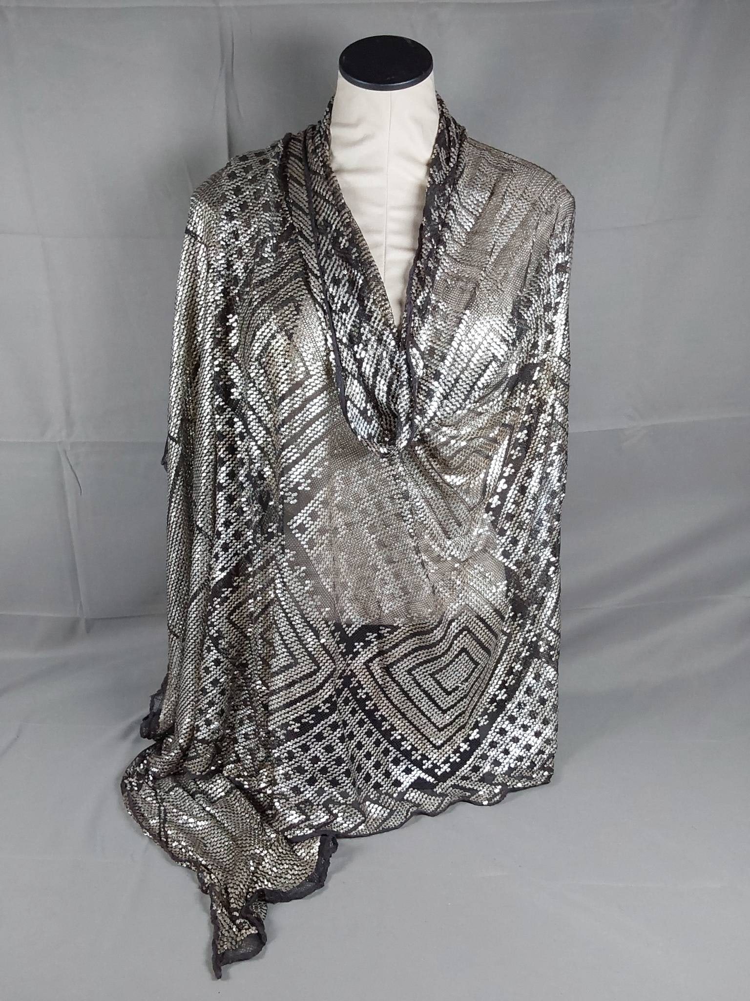Vintage Black and Silver Assiut Shawl: Vintage black and silver Assiut shawl featuring black cotton netting or mesh adorned with woven silver strips in a diamond pattern. Silver embellishments add considerable heft to this beautifully craf