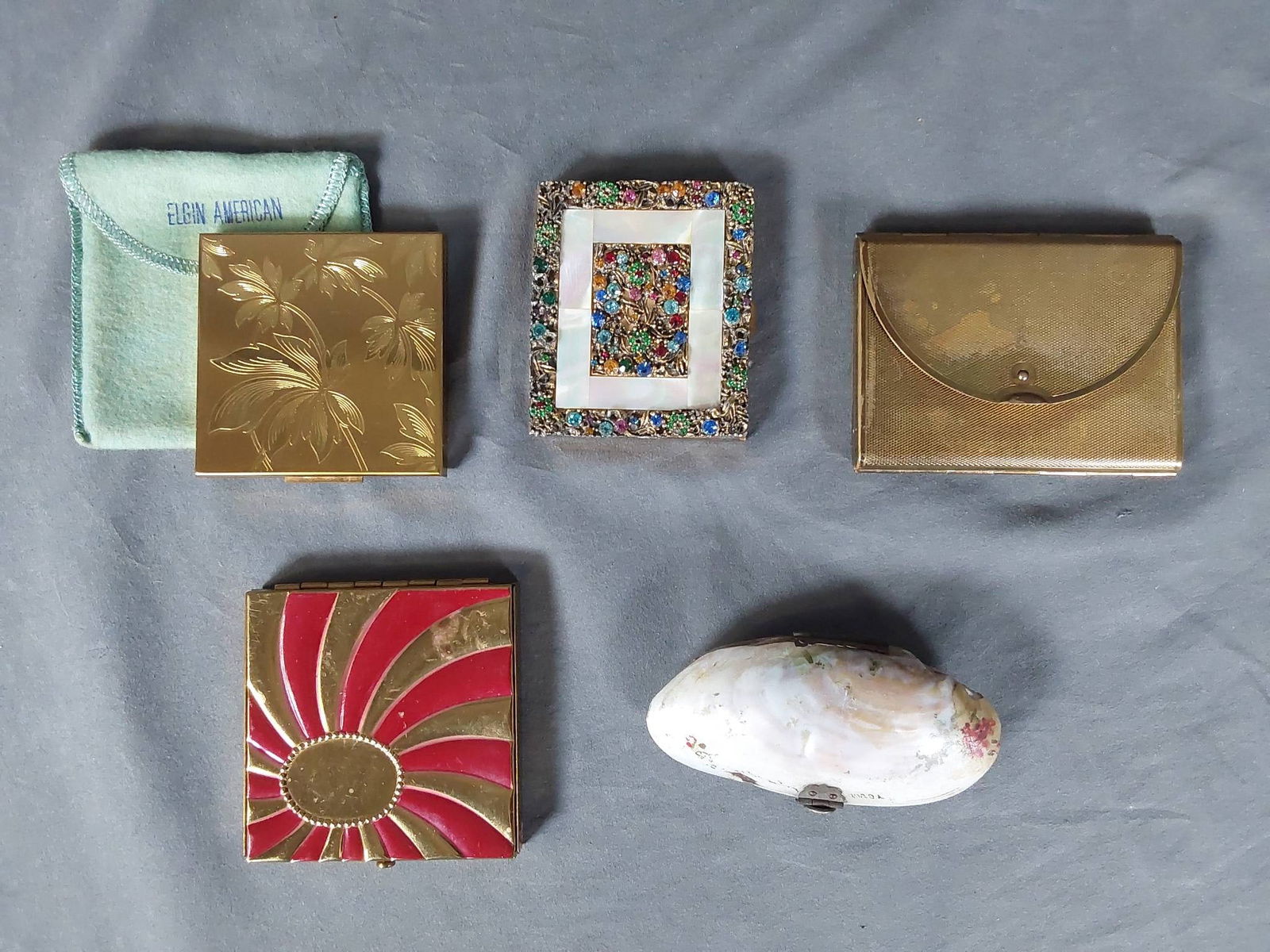 Group of 5 Vintage Makeup Compacts: Group of 5 vintage compacts featuring the following pieces: an Elgin American gold tone compact with etched leaf design, measuring 3 x 3 inches in good condition; a Cody gold tone envelope-style compa