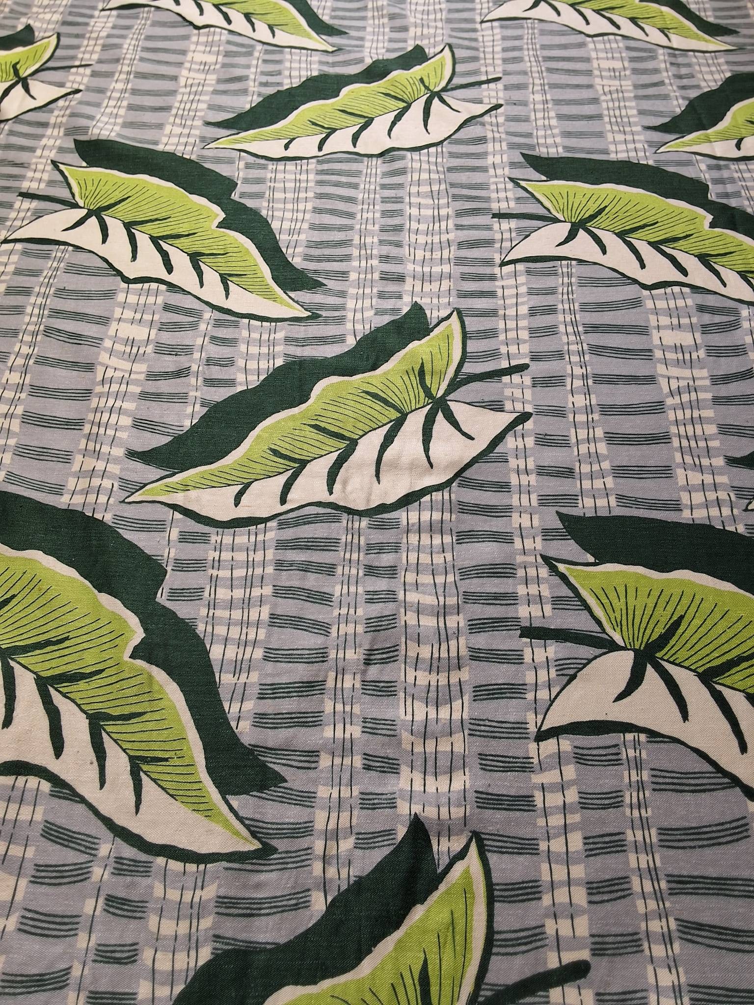 Vintage Fabric - Tropical Print: Lot consisting of 2 pieces of fabric measuring 46inx205in and 46inx111in. The fabric features a grey and white background with large two by toned leaves in ivory and lime green. Dark green veins and s