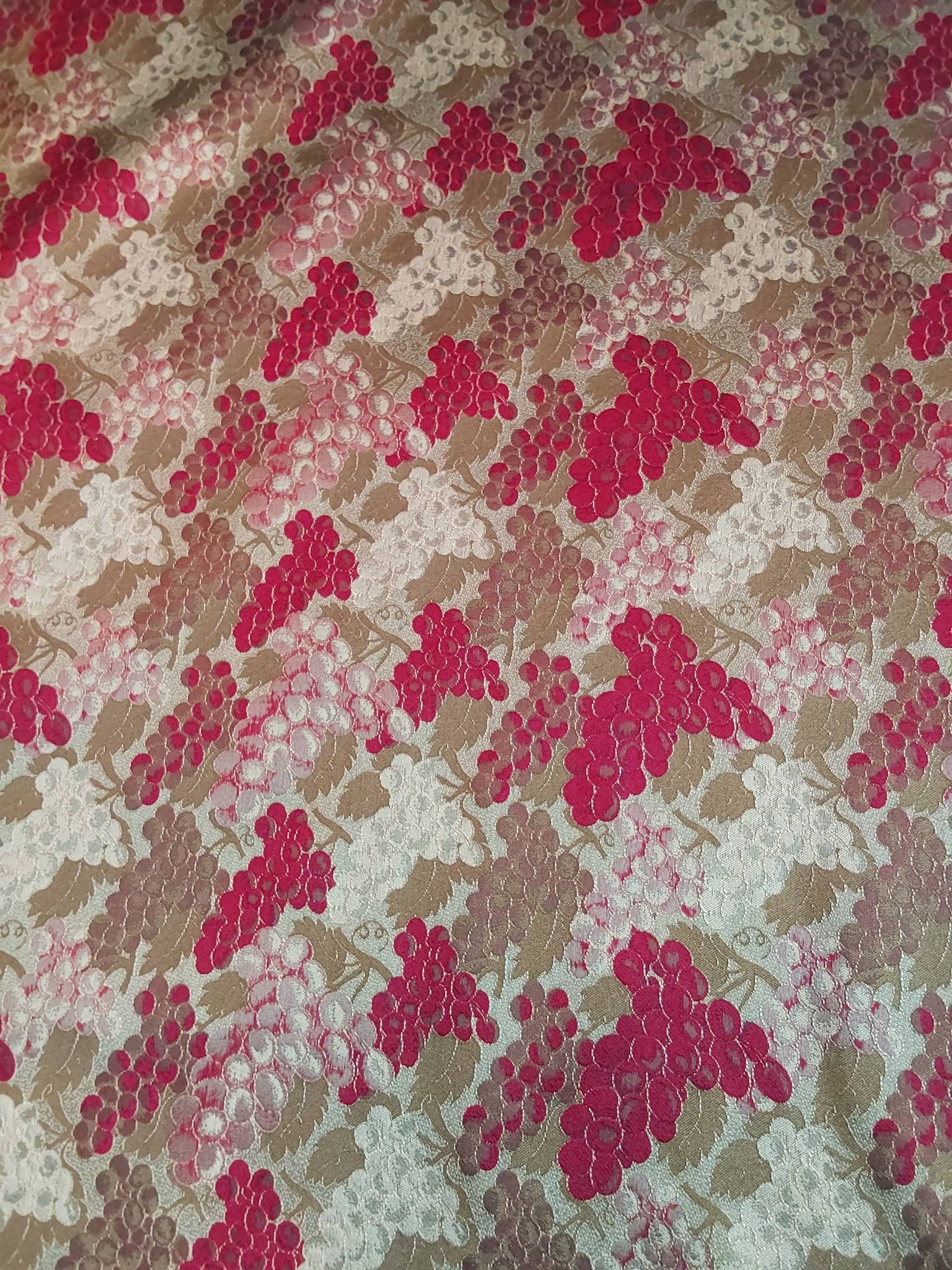 Vintage Fabric - Grapes: A vintage reversible fabric featuring grape motifs with vines and leaves. The reverse showcases a sage green background with grapes outlined in gold thread, while the front side features a red backgro