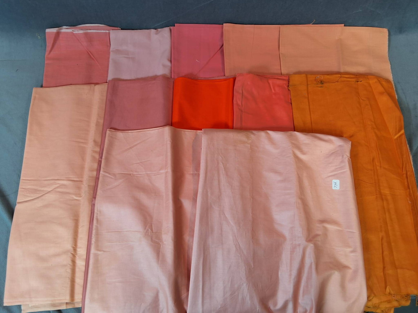 Collection of Fabric in Peachy Hues: An assortment of 12 fabric pieces in various shades of peach, along with orange and gold tones. The lot totals 3.11 lbs and includes a variety of measurements. Two pieces show signs of wear, including