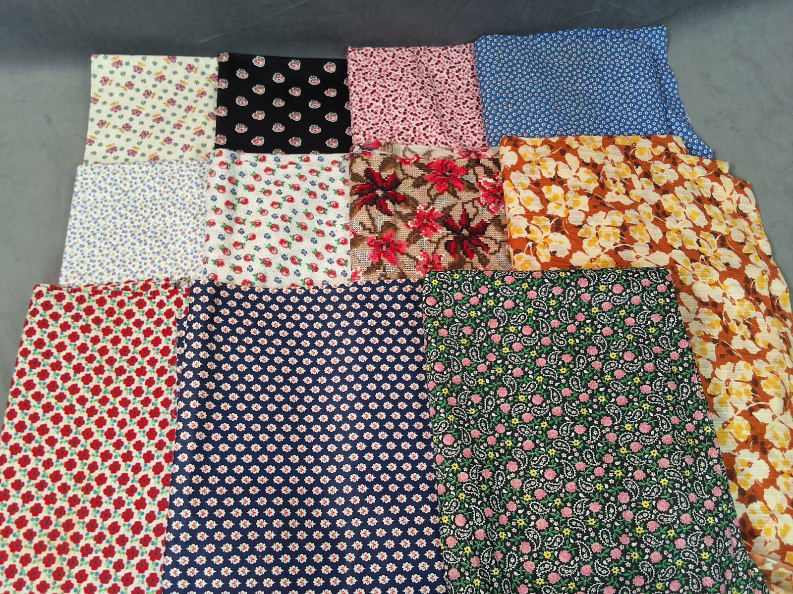 Vintage Cotton Fabric - Florals and Paisleys: Lot consisting of 11 pieces of vintage cotton fabric with a combined weight of 5.03 lbs. Patterns include a variety of florals and some paisleys, with prominent shades of pink, white, blue, red, green