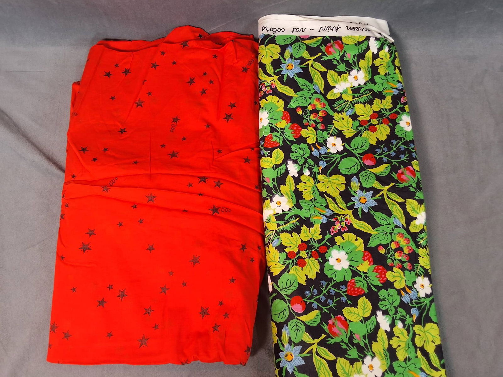 Vintage Cotton Fabric - Stars and Florals: A vintage cotton fabric lot consisting of two pieces weighing 2.15 lbs. The first fabric measures 42in by 303in and features a vibrant red background with black stars in various sizes. The second piec