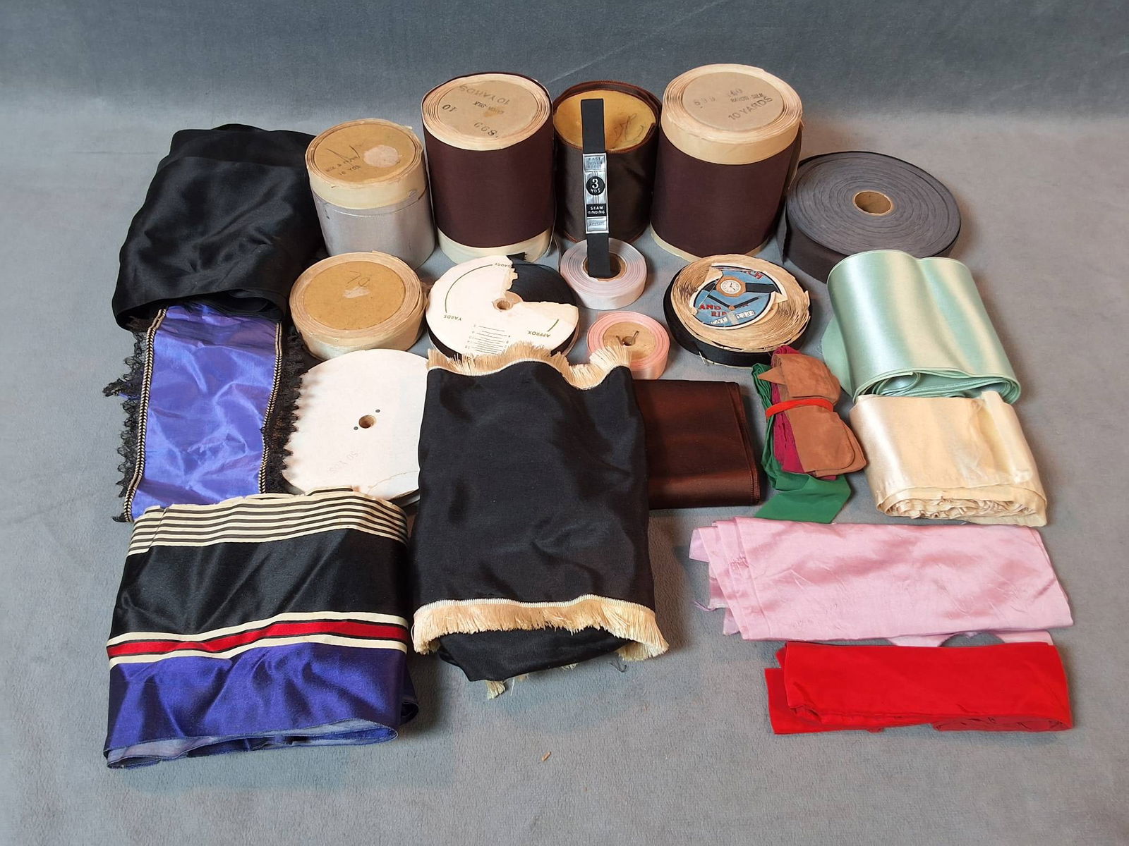 Vintage Satin Ribbon Trim Collection: A collection featuring 24 vintage satin ribbon trims made from a silk and rayon blend, with one piece composed of acetate. This assortment includes trims in colors such as black, grey, pink, brown, gr