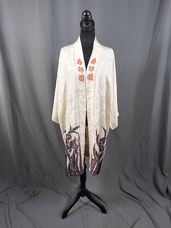 Vintage White Kimono with Accents: Vintage White Kimono with Accents. The lot consists of a vintage white kimono with lettering and florals. Featured is a white kimono with orange lettering and florals on the bottom and back. There is 