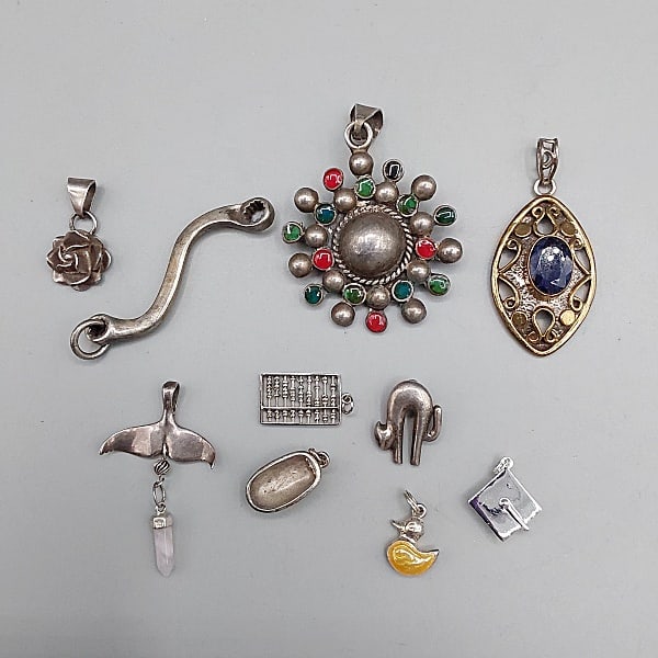 10 Sterling Silver Pendant or Charms: 10 Sterling Silver Pendant or Charms. 6 small charms all marked sterling or 925: Whale Tail, Abacus, Cat, Bath tub, Duck, Graduation Cap. A 925 wrench pendant, 2 tone 925 filigree pendant with blue st