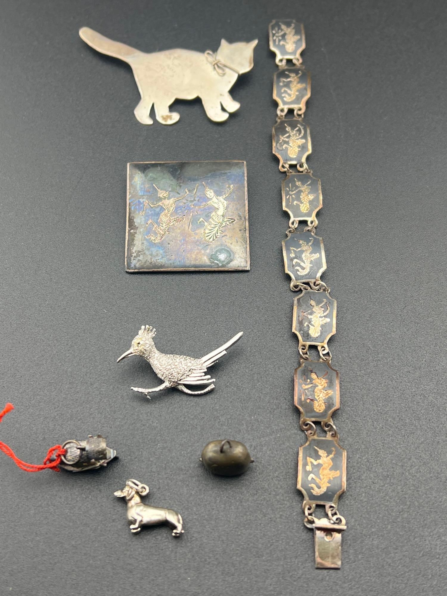 Sterling and Unmarked Silver Jewelry: Siam enamel over sterling bracelet and brooch, a sterling cat brooch, a sterling roadrunner brooch plus three unmarked charms with silver contentIf you have any doubt, please ask questions! We will pr