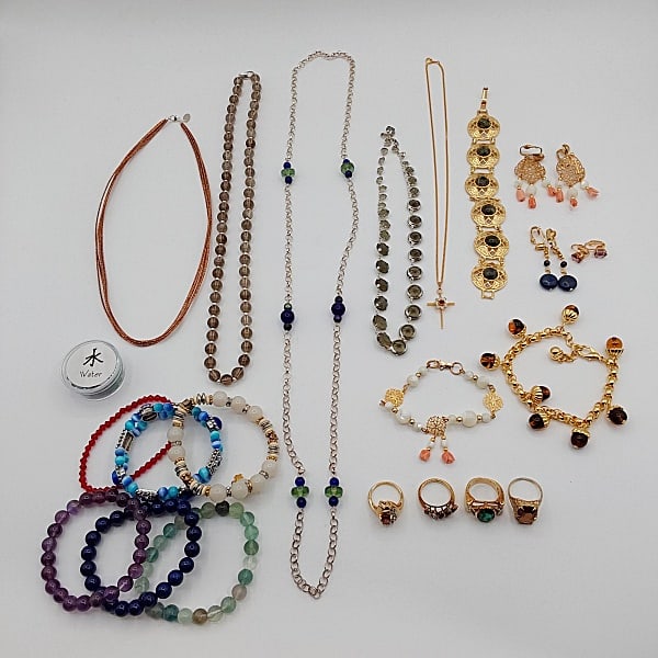 Costume Jewelry Lot: A grouping of costume jewelry that includes glass and stone beads, glass beaded necklaces; gold-tone bracelets with glass stones and green stone cabochons; a mother-of-pearl and coral bracelet and ear