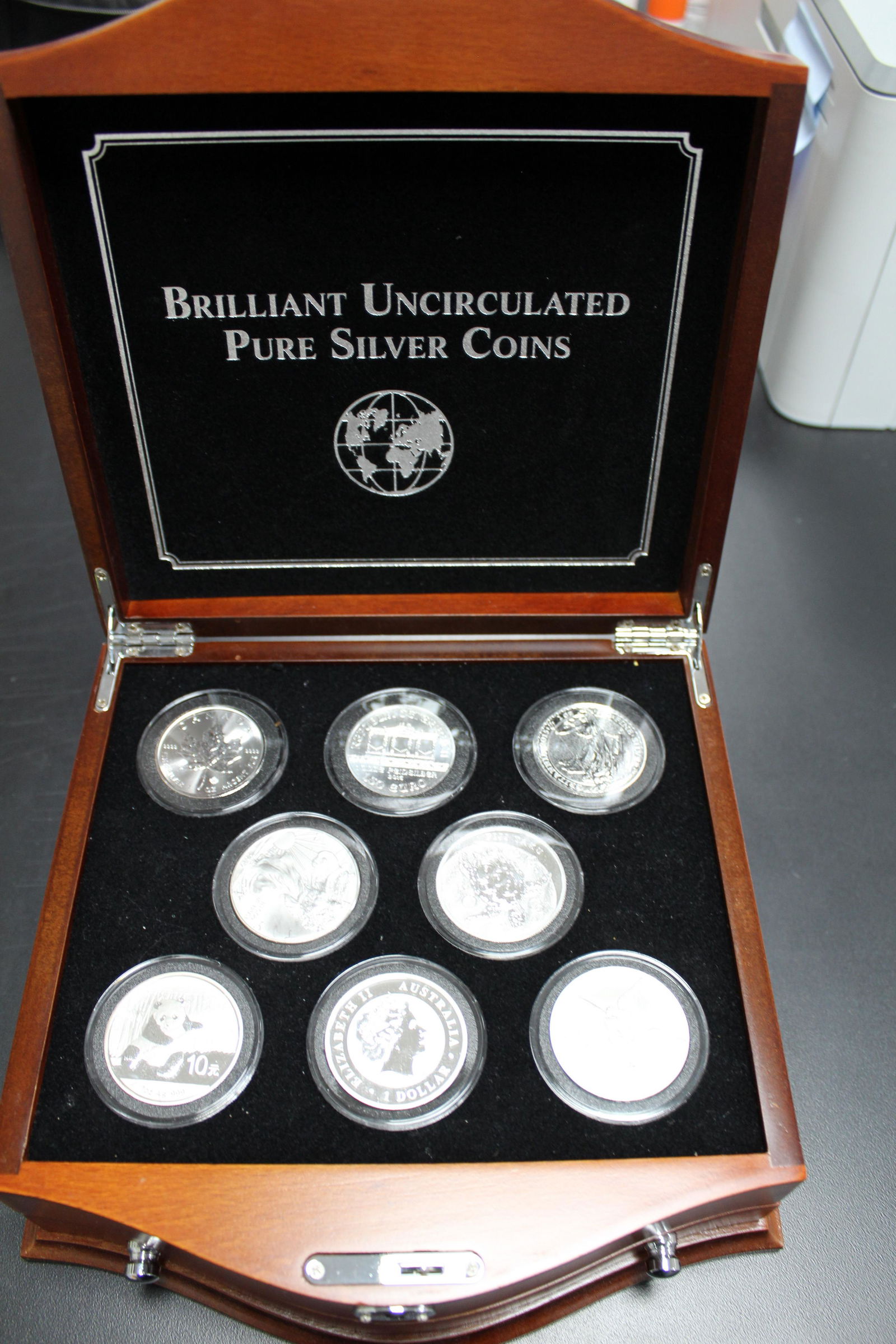 Silver Coins of the World in Wood Display Case: Includes Canada 1oz maple, Austria Philharmonic, Great Britain Elizabeth, US Silver Eagle, Fiji $2, China panda, Australian koala, and Mexico Onza. All 1 oz fine silver. 8 pieces