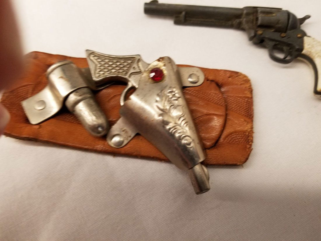 Miniature Marx cap Gun + Gun & Leather Holster: here are two nice miniature guns, one is Marx, the other one is cast metal with a leather holster and over sized bullet, marx is 3 1/2 inches long.
