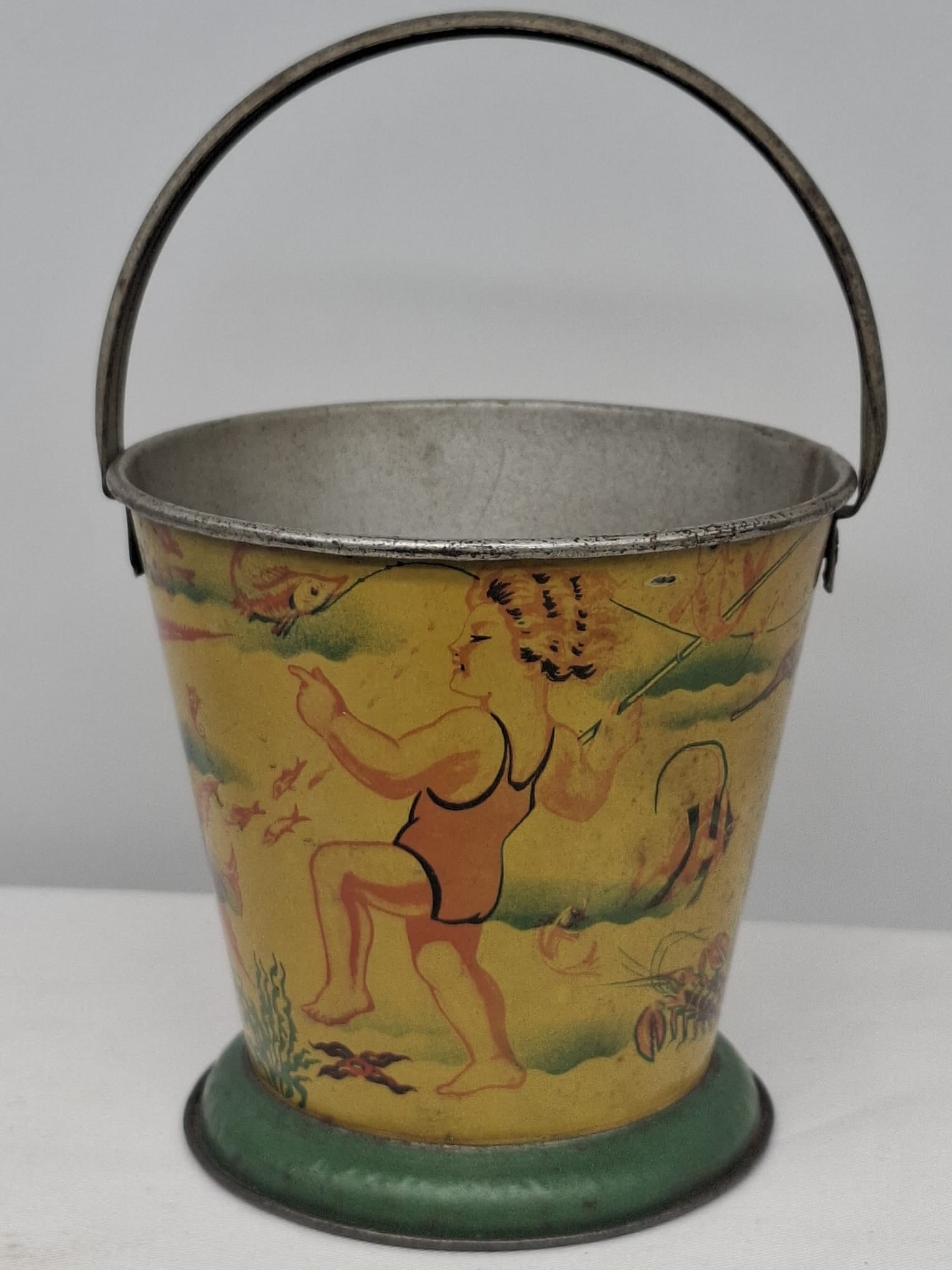 Early 20th Century Lithographed Tin Sand Pail – From Extensive European Collection: A charming and increasingly scarce early 20th century lithographed tin sand pail, exemplifying the colorful and imaginative design of classic seaside toys. This piece features vibrant period lithograp
