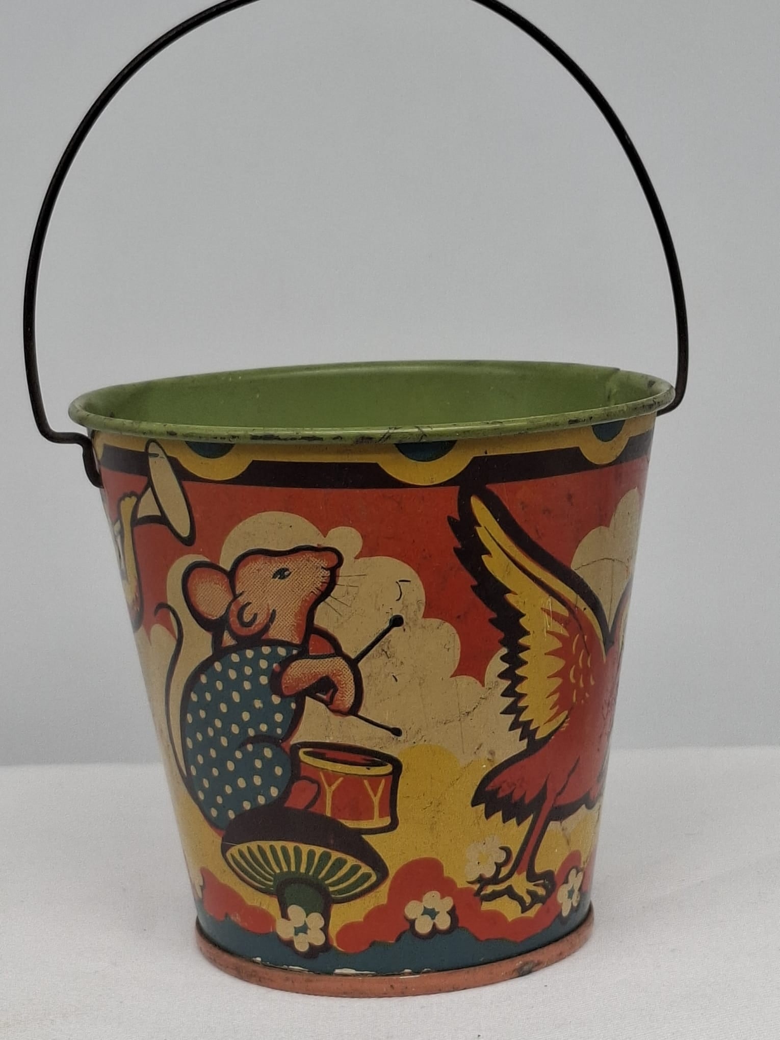 Early 20th Century Lithographed Tin Sand Pail – From Extensive European Collection: A charming and increasingly scarce early 20th century lithographed tin sand pail, exemplifying the colorful and imaginative design of classic seaside toys. This piece features vibrant period lithograp