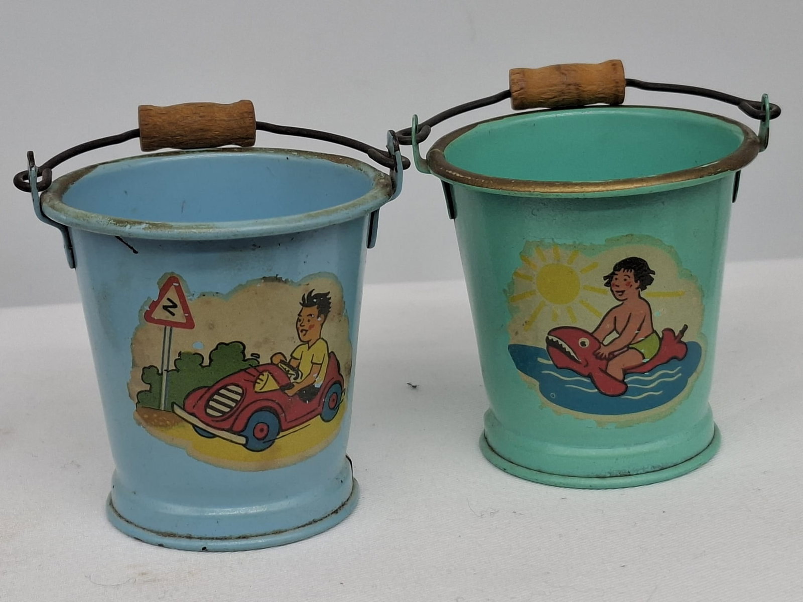 Early 20th Century Lithographed Tin Sand Pail – From Extensive European Collection: A charming and increasingly scarce early 20th century lithographed tin sand pail, exemplifying the colorful and imaginative design of classic seaside toys. This piece features vibrant period lithograp