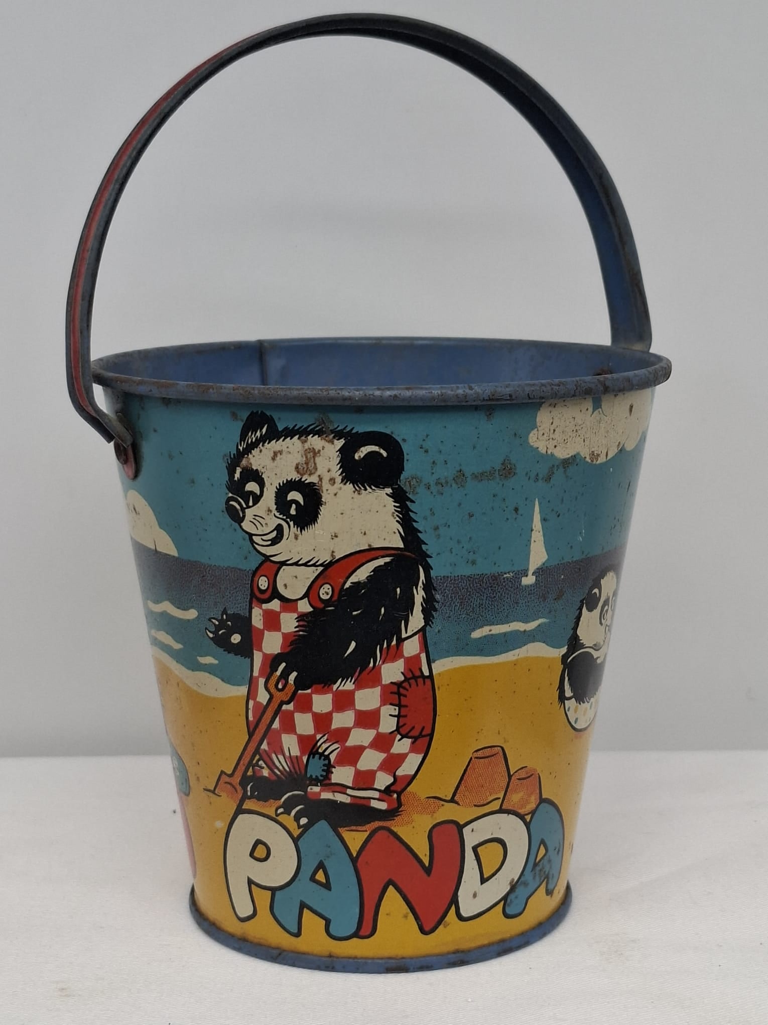 Early 20th Century Lithographed Tin Sand Pail – From Extensive European Collection: A charming and increasingly scarce early 20th century lithographed tin sand pail, exemplifying the colorful and imaginative design of classic seaside toys. This piece features vibrant period lithograp